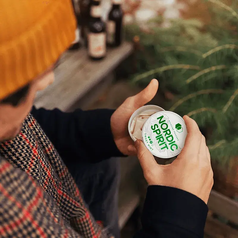 Lifestyle shot showing a can of Nordic Spirit Sweet Mint Nicotine pouches in the hands of a man.