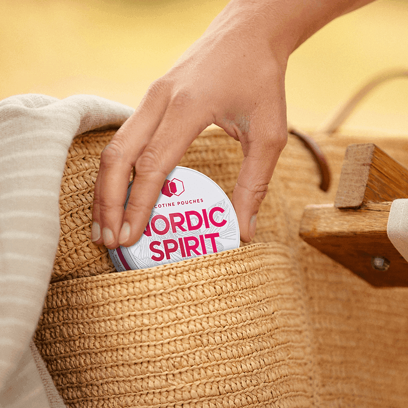 A can of Nordic Spirit Raspberry Nicotine Pouches being placed into a beach bag.