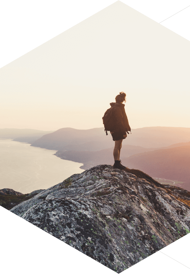 Hiker standing atop a mountain looking out over the landscape.